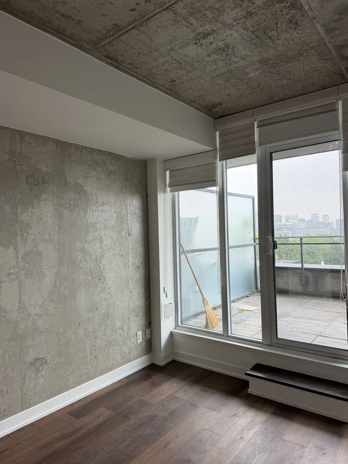 Repainted condo living area with exposed concrete wall and balcony access