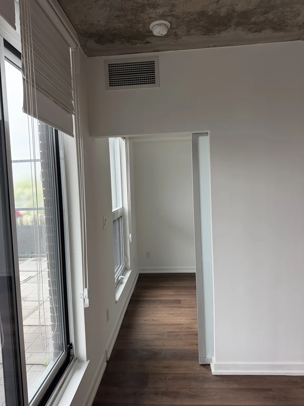 Bright repainted condo den with large windows and roller shades after turnover refresh