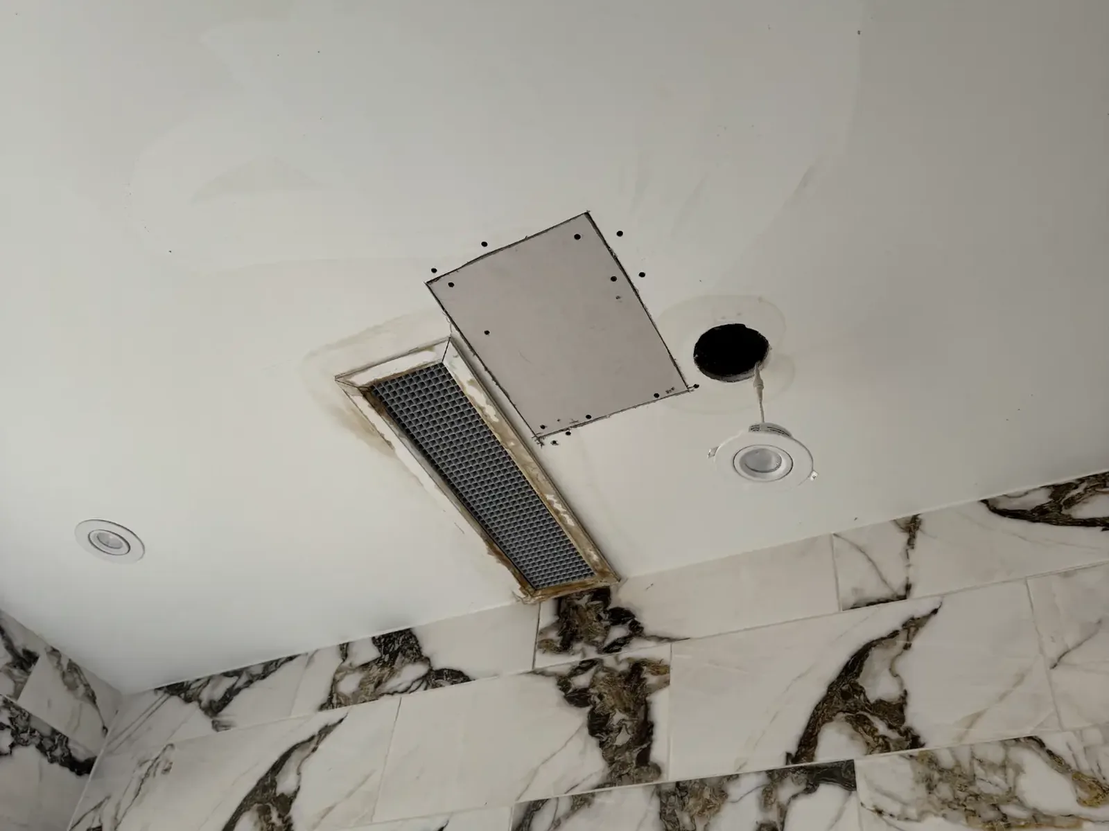 Cut-open ceiling around an HVAC vent before drywall repair
