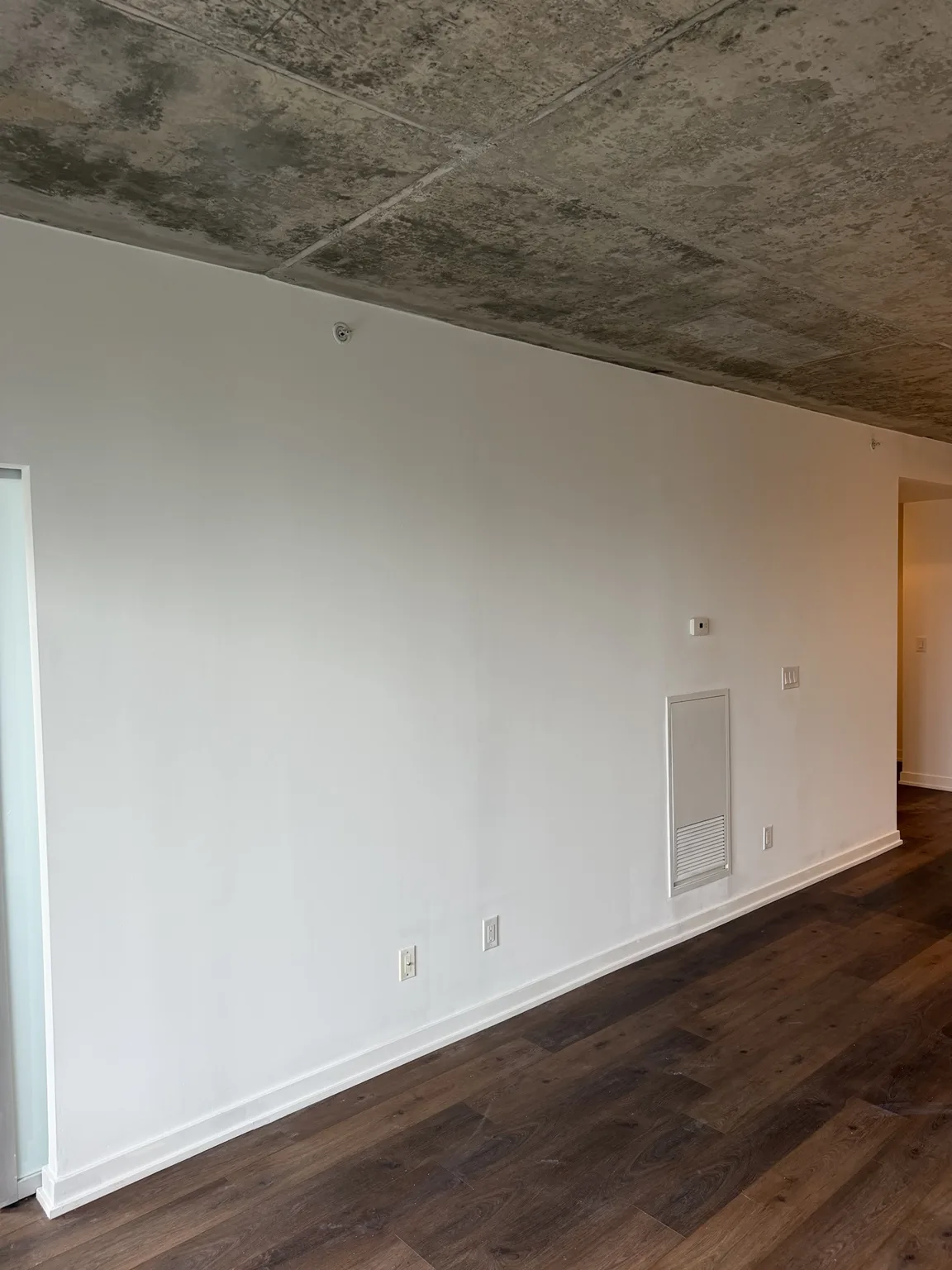 Repainted condo living room wall with new baseboards and dark laminate flooring